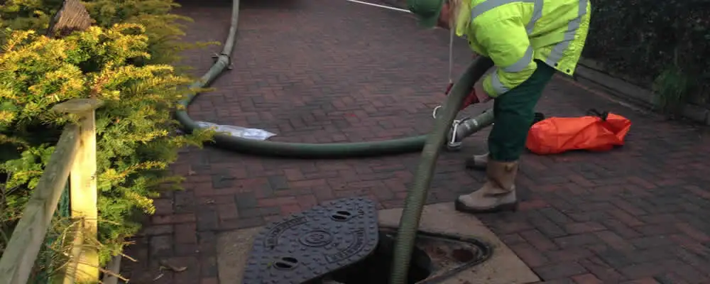 Septic tank cleaning technician servicing a septic tank with a vacuum hose in Naperville, IL