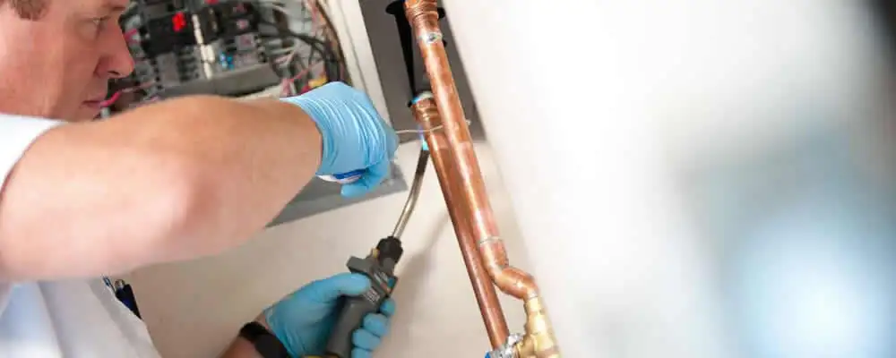 Water heater repair technician testing copper pipe connections and controls in Naperville, IL